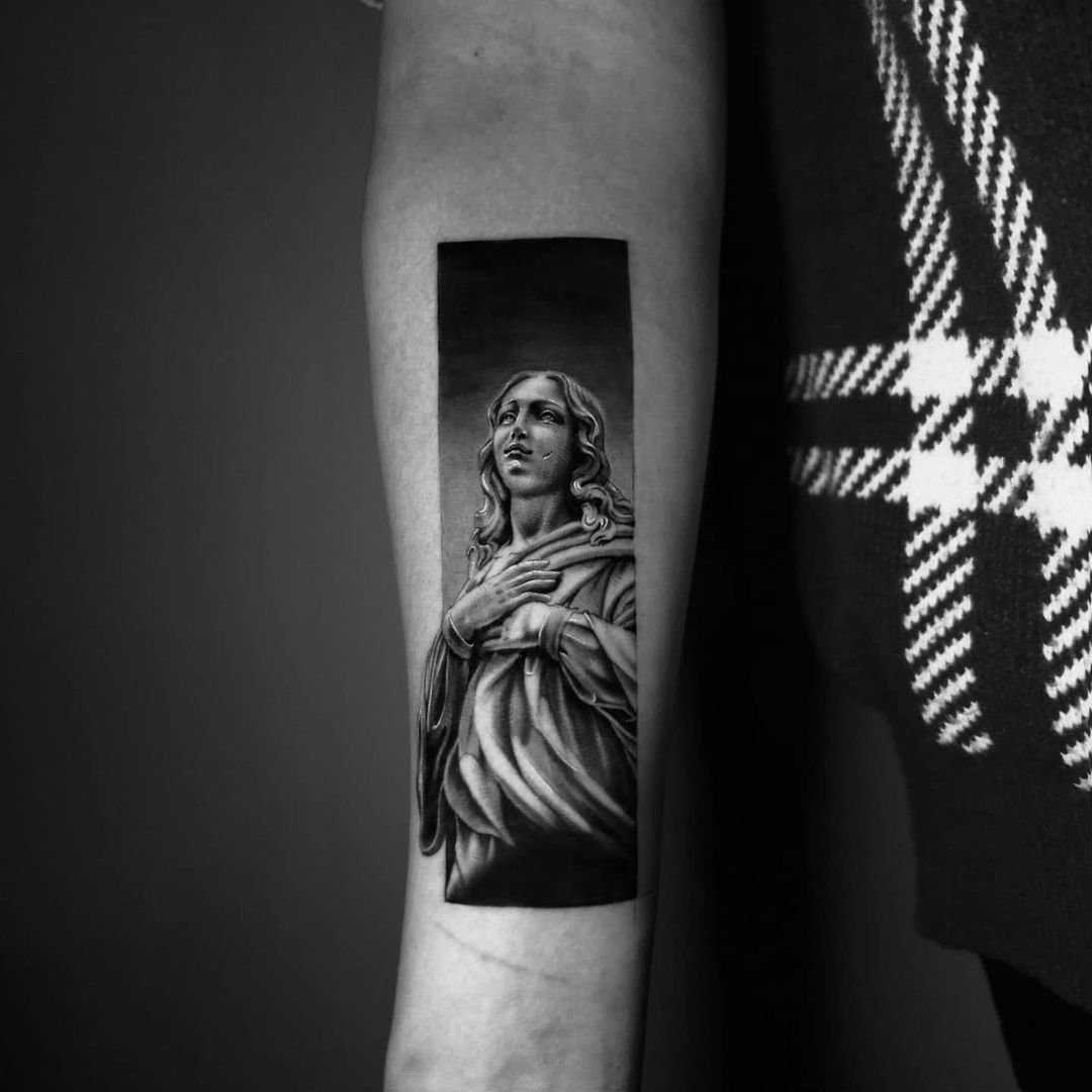 Realistic black and grey tattoo of a religious figure