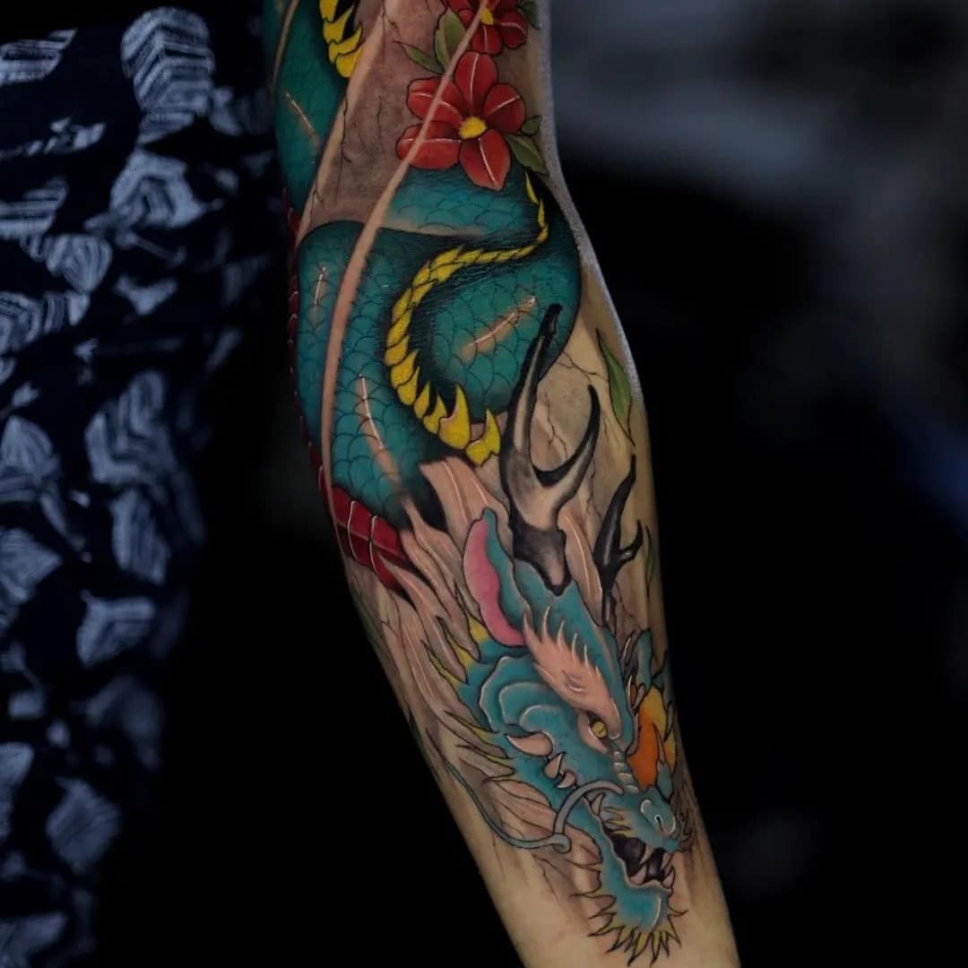 Colorful dragon tattoo on forearm with floral details