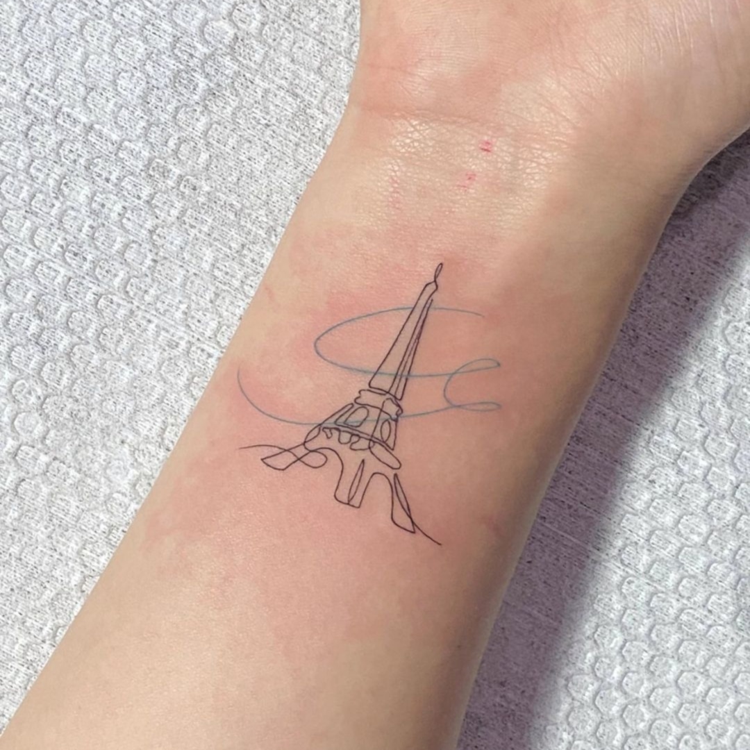 Minimalist tattoo of the Eiffel Tower on wrist