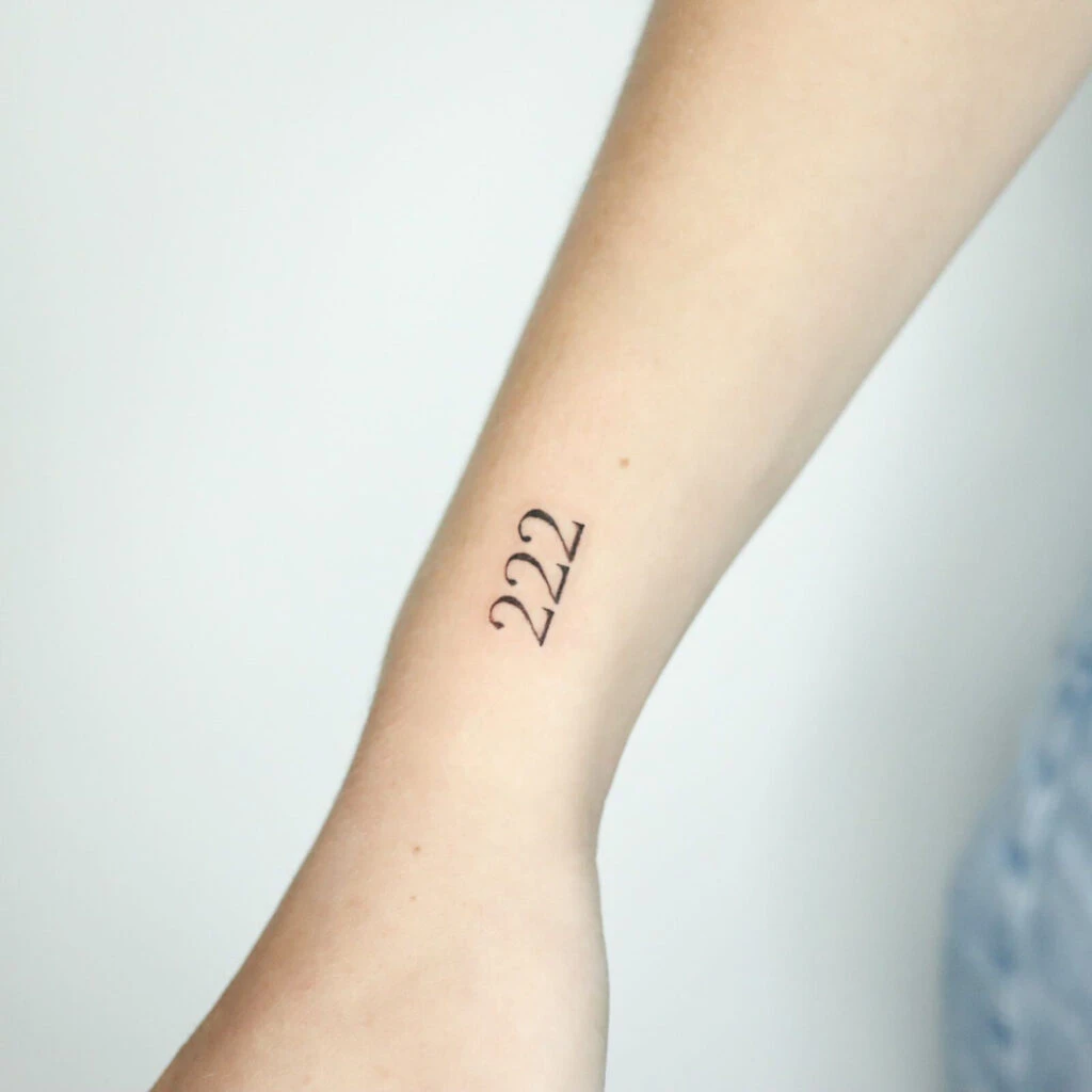 Minimalist tattoo with the numbers 222 on an arm