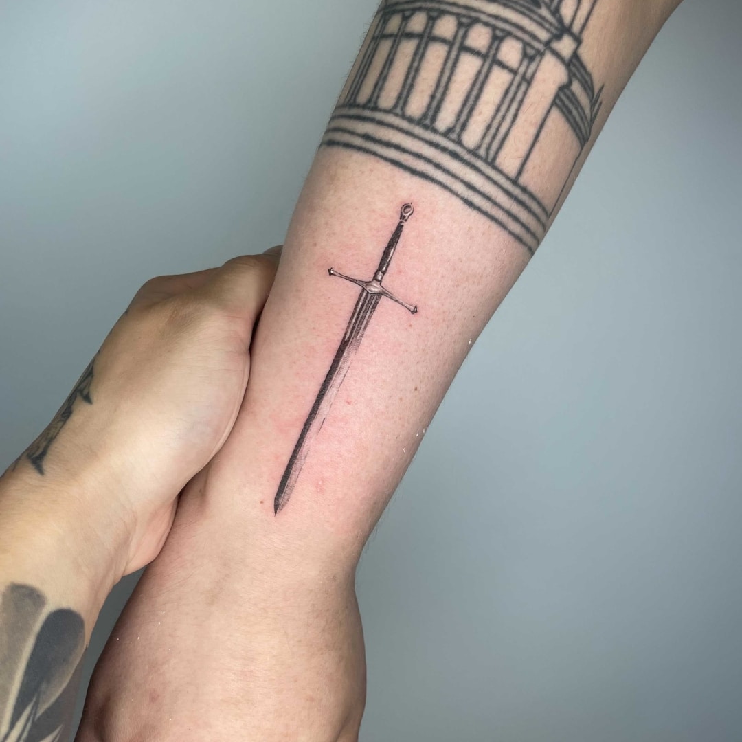 Detailed tattoo of a sword on a person's forearm