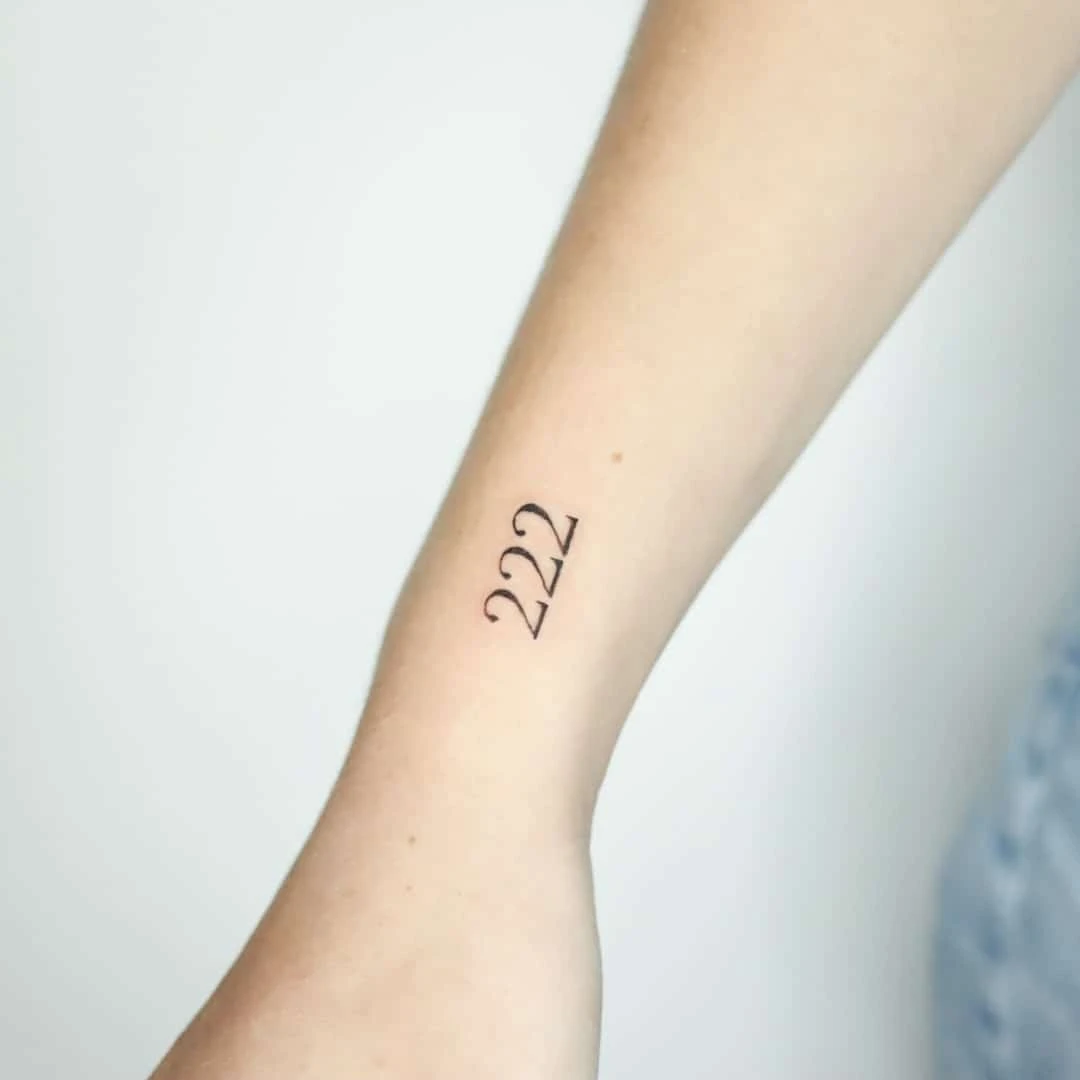 Close-up of a tattoo displaying the number 222 on a wrist.