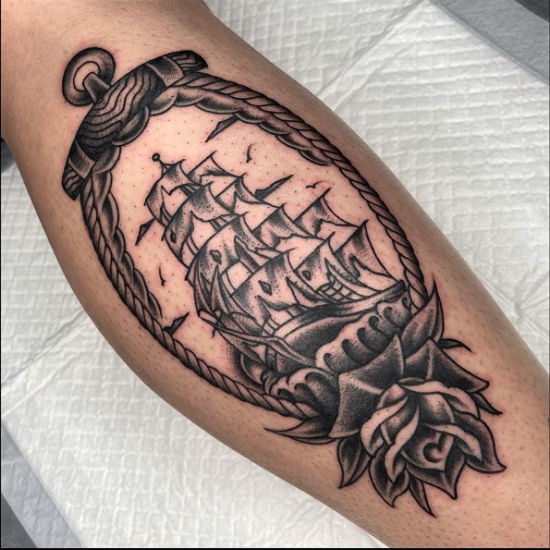 Bice tattoo of a ship framed by a rope and rose.